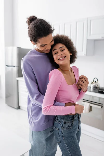 Homem americano africano positivo de mãos dadas de namorada alegre em casa — Fotografia de Stock