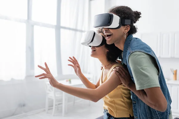 Positive african american couple in vr headsets gaming at home — Fotografia de Stock