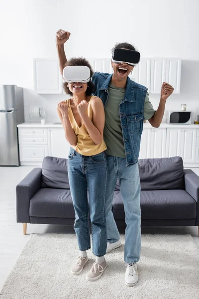 Couple afro-américain excité montrant un geste oui tout en jouant dans des casques vr à la maison — Photo de stock