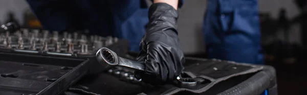 Vista cortada de mecânico em luva segurando chave na garagem, banner — Fotografia de Stock