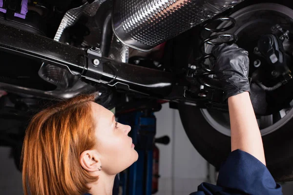 Side view of redhead mechanic working with car in service — Stock Photo