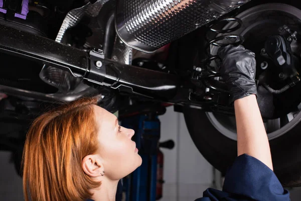 Side view of redhead mechanic working with car in service — Fotografia de Stock