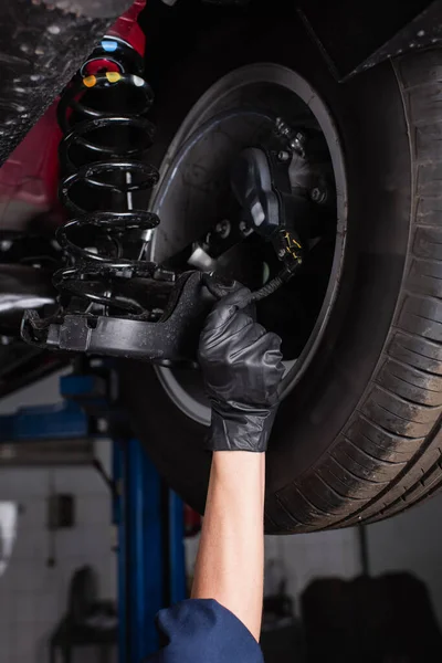 Cropped view of workwoman in glove working with car wheel in garage — Stockfoto