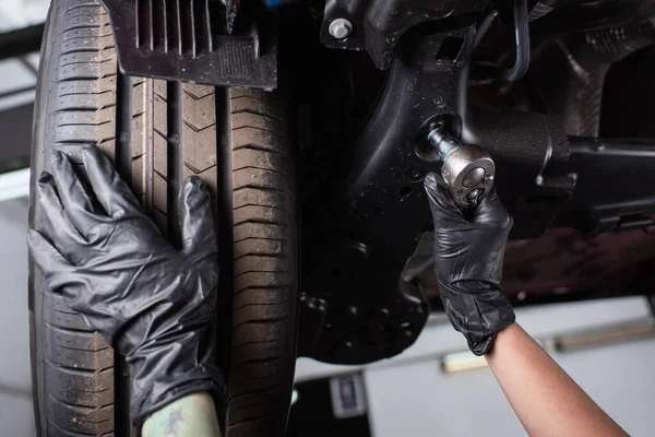 Ausgeschnittene Ansicht des Mechanikers in Handschuhen, der mit Schraubenschlüssel in der Nähe des Fahrzeugs in der Garage arbeitet — Stockfoto