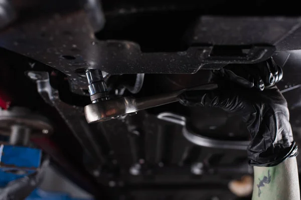 Cropped view of workwoman using tool while working in car service — Stock Photo