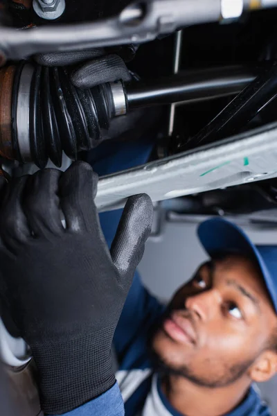 Meccanico afroamericano sfocato in guanti che lavora con auto in garage — Foto stock