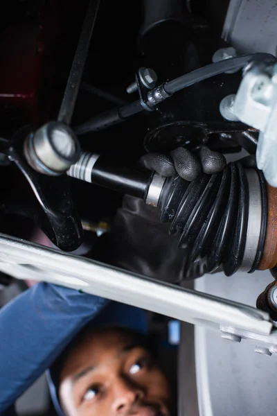Unscharfer afrikanischer Techniker überprüft Stoßdämpfer des Autos — Stockfoto