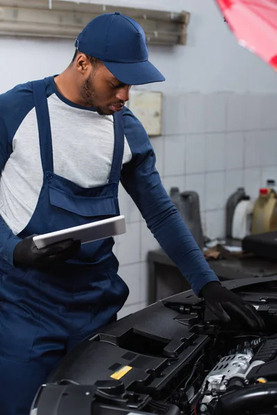 Afrikanisch-amerikanischer Arbeiter mit digitalem Tablet inspiziert Auto in Auto-Tankstelle — Stockfoto