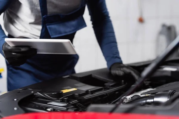 Vista parziale del caposquadra ritagliato con tablet digitale vicino al vano motore dell'auto — Foto stock