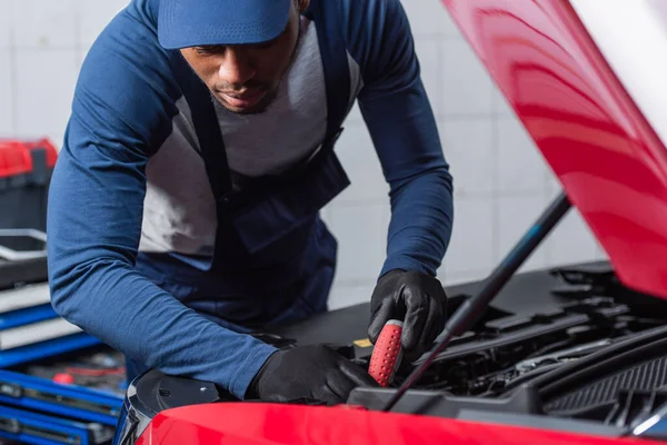 Junger afrikanisch-amerikanischer Mechaniker macht Diagnose des Autos in der Werkstatt — Stockfoto
