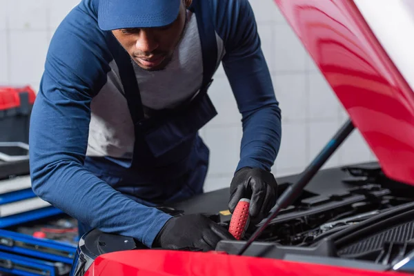 Giovane meccanico afroamericano che fa diagnosi di auto in officina — Foto stock