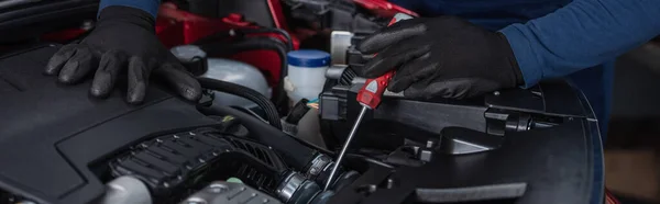 Partial view of mechanic in work gloves repairing car engine with screwdriver, banner — Stock Photo