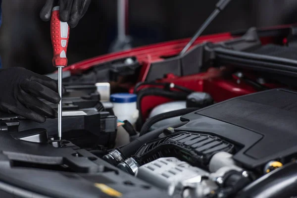 Cropped view of mechanic in work gloves inspecting car engine compartment with screwdriver — Stock Photo
