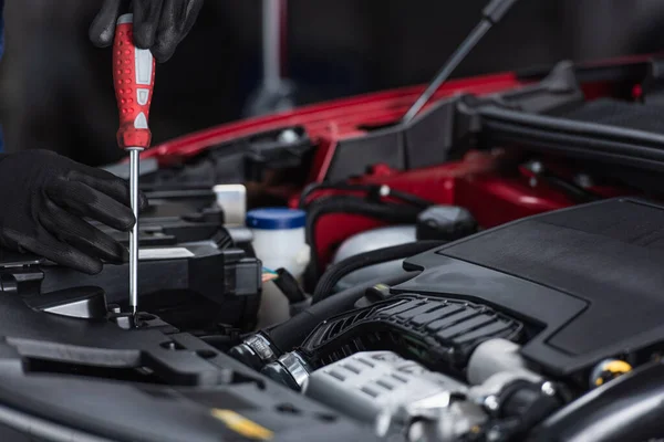 Cropped view of mechanic in work gloves inspecting car engine compartment with screwdriver — Stockfoto