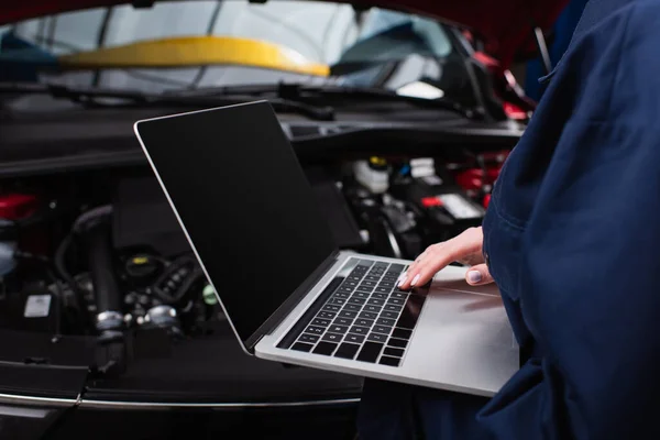 Vista parziale della donna di fronte con il computer portatile che fa la diagnostica dell'automobile offuscata in servizio — Foto stock