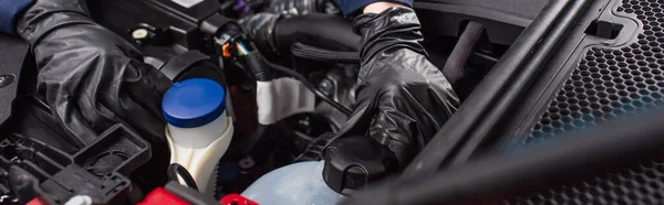 Partial view of mechanic in work gloves checking engine compartment of vehicle in car service, banner — Stock Photo