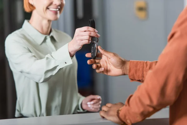 Cropped view of blurred car dealer giving key to african american customer — Stock Photo