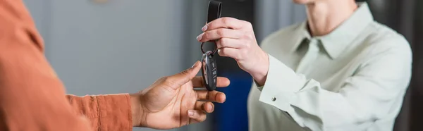 Vue partielle du concessionnaire automobile donnant la clé au client afro-américain, bannière — Photo de stock