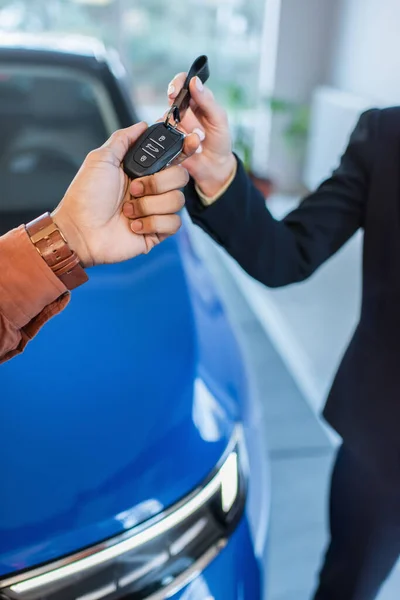 Cropped view of african american man taking key from car dealer near blurred car — Stock Photo