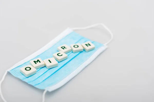 White cubes with omicron lettering on medical mask on grey background — Photo de stock