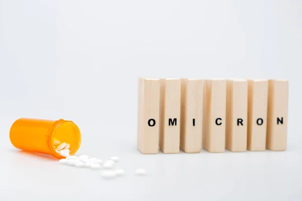 Wooden bricks with omicron lettering near pills on grey background — Photo de stock