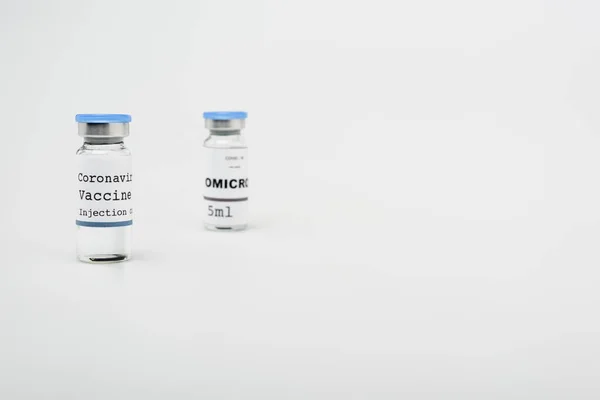 Flacons avec vaccin covid-19 et omicron sur fond gris avec espace de copie — Photo de stock