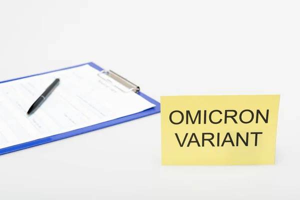 Card with omicron variant lettering near clipboard with medical card and pen on grey — Stock Photo