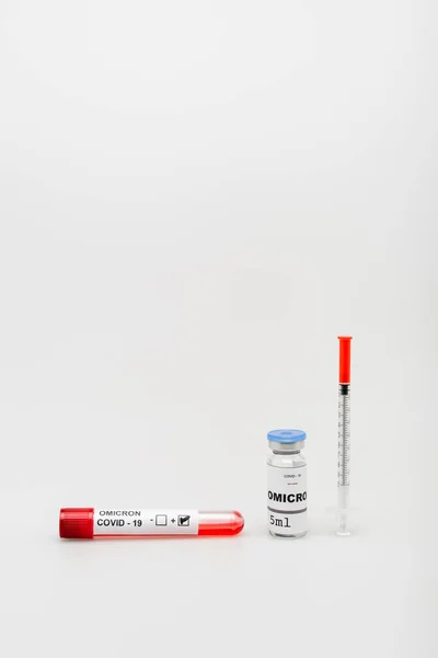 Test tube with positive result near covid-19 omicron variant vaccine and syringe on grey background — Photo de stock