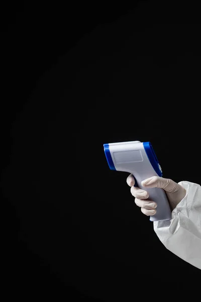 Cropped view of doctor in latex glove holding pyrometer isolated on black with copy space — стоковое фото