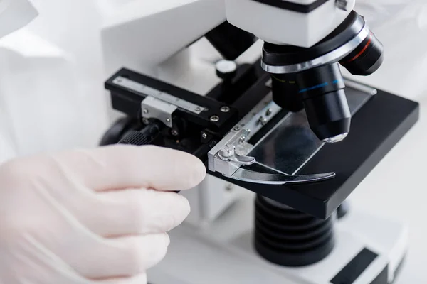 Vista parcial del biólogo que trabaja con microscopio en laboratorio médico - foto de stock