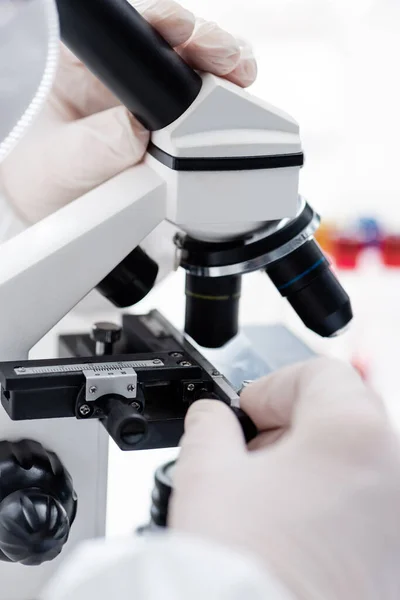 Cropped view of biologist working with microscope in science laboratory, omicron variant concept — Photo de stock