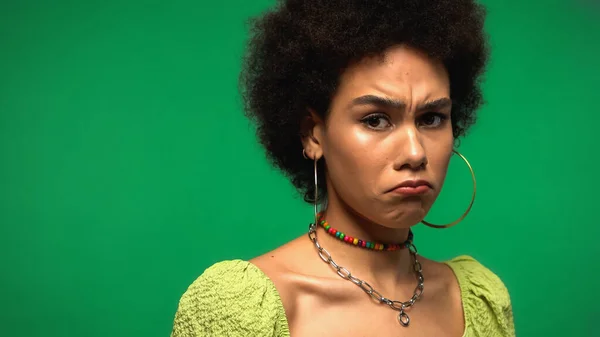 Bouleversé afro-américaine femme fronçant les sourcils et regardant la caméra isolée sur vert — Photo de stock