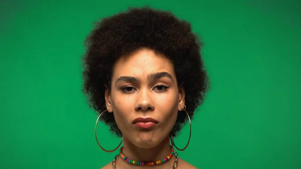 Skeptical african american woman looking at camera isolated on green — Stock Photo