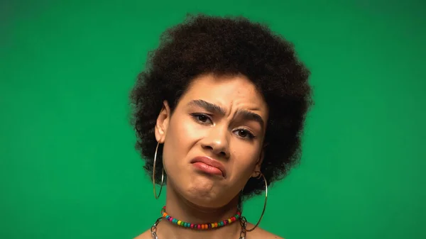 Displeased african american woman looking at camera isolated on green — стоковое фото