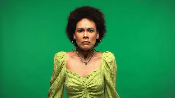 Mujer afroamericana insatisfecha mirando la cámara aislada en verde - foto de stock