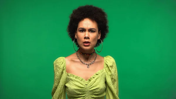 Dissatisfied young african american woman looking at camera isolated on green — Fotografia de Stock