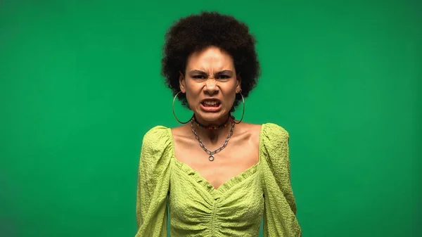 Femme afro-américaine en colère regardant la caméra isolée sur vert — Photo de stock