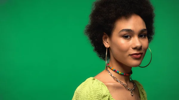 Afroamerikanerin mit Reifrohrringen blickt vereinzelt in die Kamera auf Grün — Stockfoto