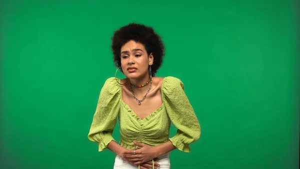 Curly african american woman in hoop earrings having stomach ache isolated on green — Fotografia de Stock