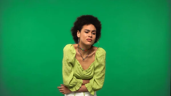 Jeune femme afro-américaine en boucles d'oreilles cerceau ayant mal au ventre isolé sur vert — Photo de stock