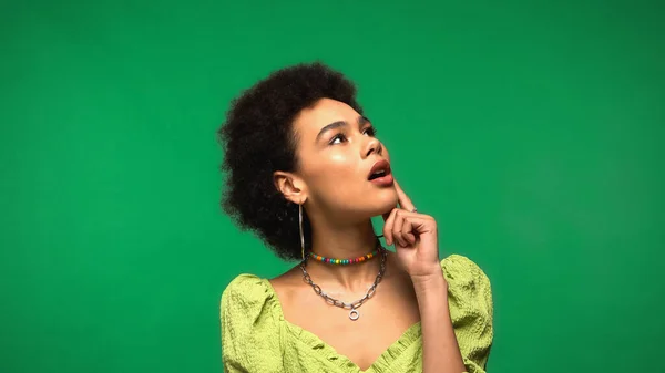 Dreamy african american woman with open mouth looking away isolated on green — Stockfoto