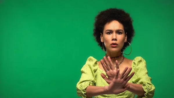 African american woman in hoop earrings showing refuse and looking at camera isolated on green — Stock Photo