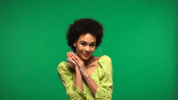 Радісна афроамериканська жінка в сережках з блузкою та обручкою ізольована на зеленому — стокове фото