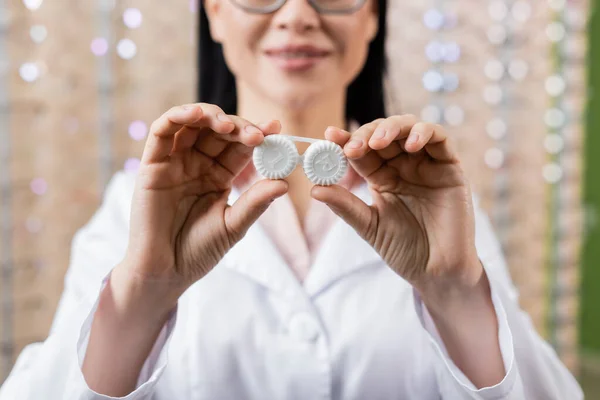 Partial view of blurred oculist showing lens case in optics salon — Stock Photo