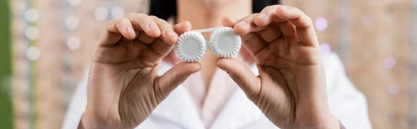 Cropped view of blurred ophthalmologist holding lens case in optics store, banner — Stock Photo