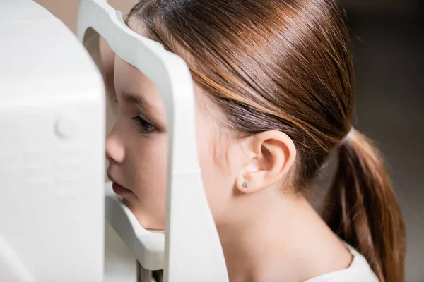 Child checking eyesight on blurred vision screener — стоковое фото