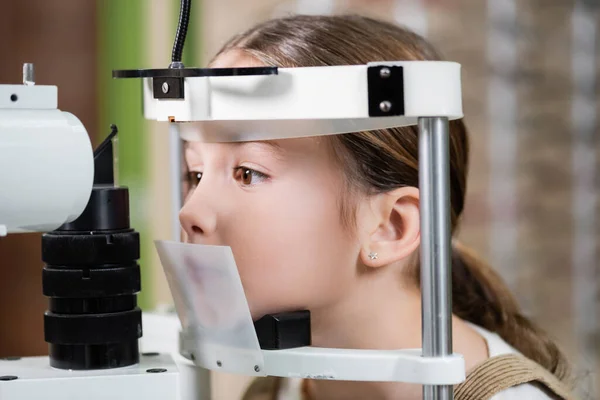 Girl checking eyesight on blurred vision screener — стоковое фото