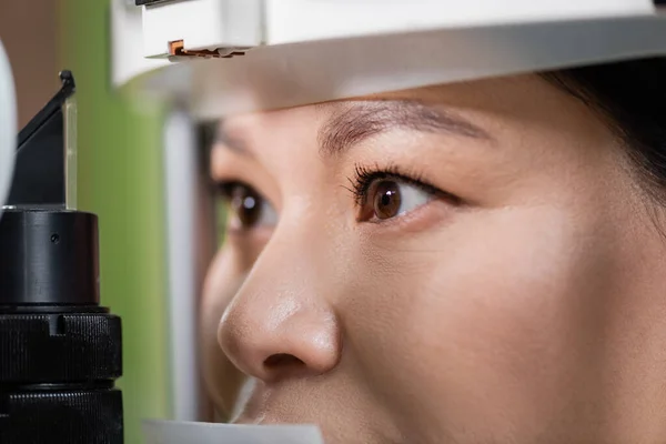 Close up view of asian woman checking eyesight on blurred vision screener - foto de stock