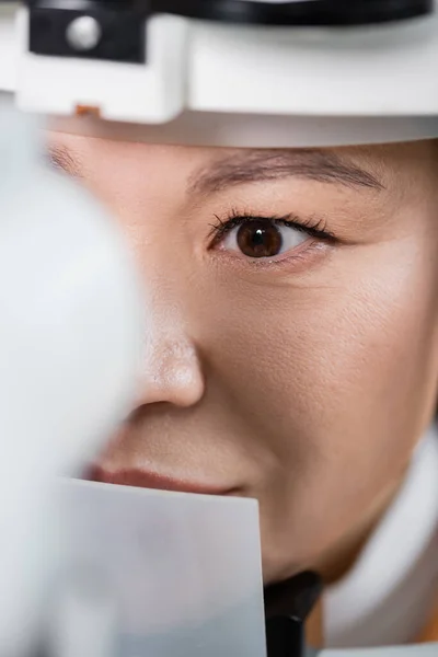 Vue rapprochée de l'optométriste asiatique travaillant avec un écran de vision au premier plan flou — Photo de stock