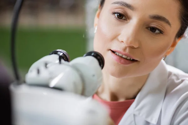 Positive optometrist working with vision screener on blurred foreground — Stock Photo